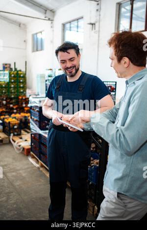 Warehouse worker and manager discussing inventory using digital tablet Stock Photo