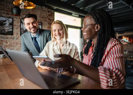 Business colleagues working together with smiling faces, analyzing data on devices Stock Photo