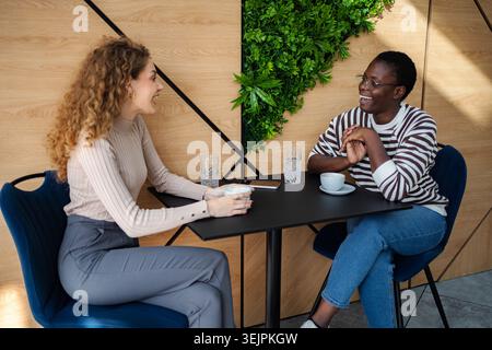 Diverse women friends enjoying conversation and coffee at cafe Stock Photo