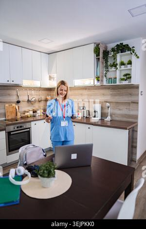 Female doctor using smartphone and laptop, working from home Stock Photo