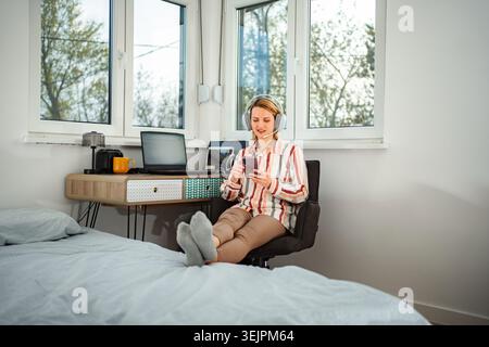 Woman working from home using headset and smartphone Stock Photo
