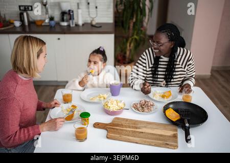 Diverse family enjoying breakfast together at kitchen table Stock Photo