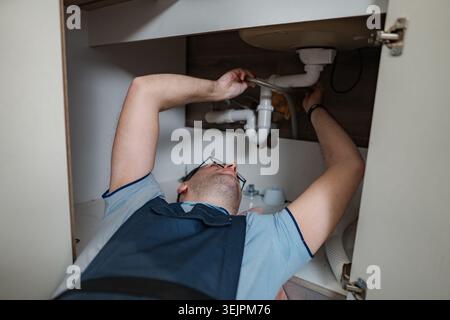Plumber working on kitchen sink plumbing repair Stock Photo
