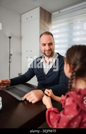 Father remote working on laptop with daughter at home Stock Photo