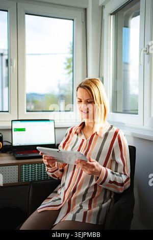 Woman working from home using digital tablet technology Stock Photo