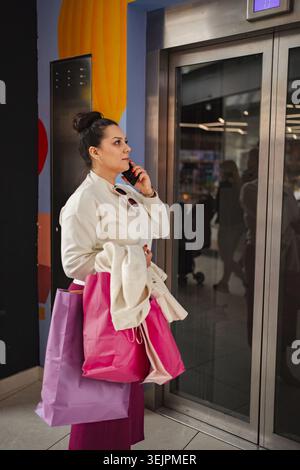 Shopping enthusiast waiting for the elevator with colorful bags Stock Photo