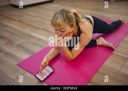 Engaging in online yoga while relaxing on a colorful mat Stock Photo