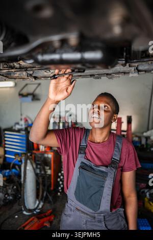 Young african female mechanic inspecting car in auto repair shop Stock Photo