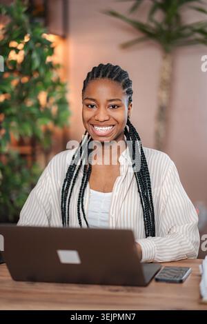 Young Black woman smiling working on laptop Stock Photo