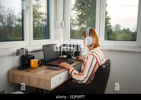 Woman working remotely from home wearing headset Stock Photo