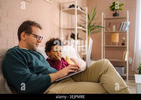 Father and son using laptop for remote work and learning Stock Photo