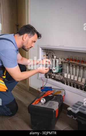 Technician checking domestic heating system with multimeter Stock Photo