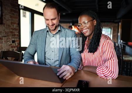 Diverse business team collaborating on laptop computer in cafe Stock Photo
