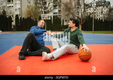 Two men shaking hands on an outdoor basketball court Stock Photo
