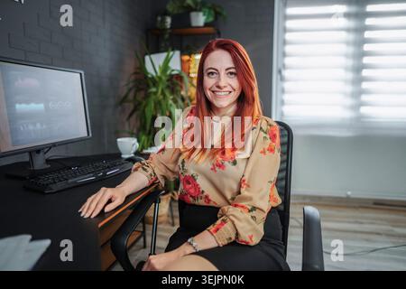 Smiling businesswoman working from home looking at camera Stock Photo