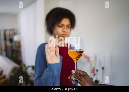 Young woman refusing a glass of wine with a serious face expression Stock Photo