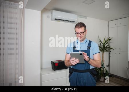 HVAC technician checking air conditioner using digital tablet Stock Photo