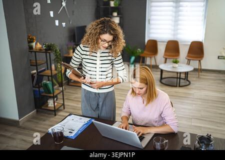 Two female colleagues working together on business report Stock Photo