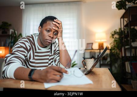 Young adult man feeling stressed and overwhelmed working from home Stock Photo