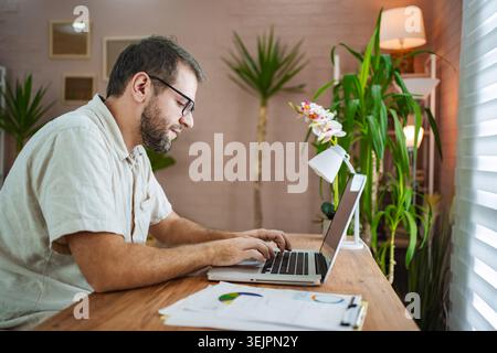 Focused man working on laptop in a stylish workspace Stock Photo
