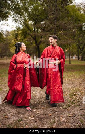 Multicultural wedding couple holding hands in traditional clothing Stock Photo