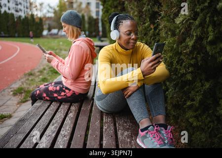 Two women using smartphones ignoring each other in park Stock Photo
