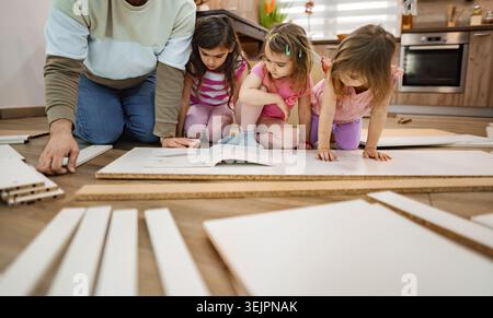 Children engaged in creative assembly in a cozy kitchen space Stock Photo