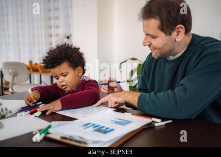 Father and son drawing together at home Stock Photo