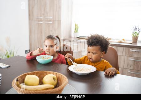 Multiracial family enjoying breakfast at home in a cozy kitchen Stock Photo