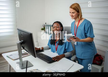 Diverse medical workers collaborating on computer and digital tablet Stock Photo