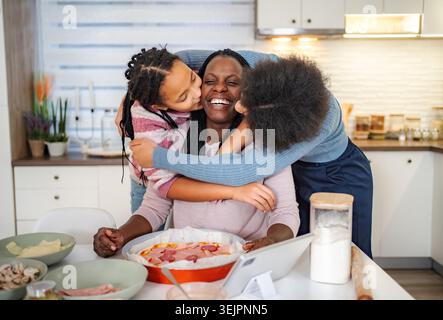 Black mother and daughters enjoying family time preparing pizza Stock Photo