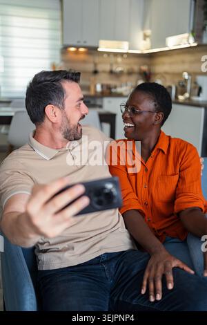 Happy multi-ethnic couple taking a selfie at home Stock Photo