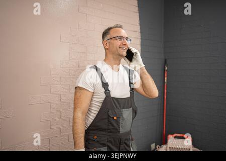 Man in Overalls Talking on Cell Phone Stock Photo