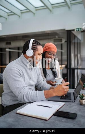 Colleagues collaborating on laptop while smiling and working in office Stock Photo