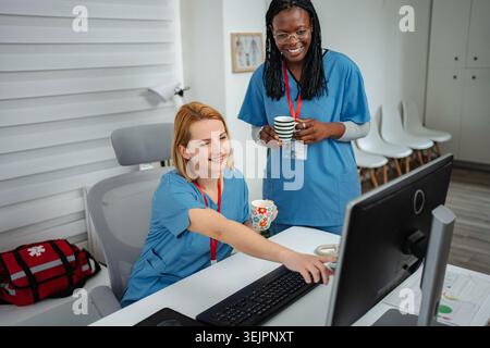 Medical team collaborating on computer during coffee break Stock Photo