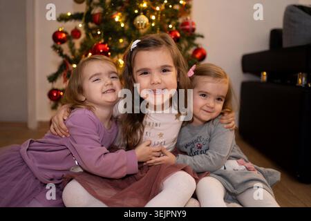 Sisters celebrating joyfully by the Christmas tree together Stock Photo