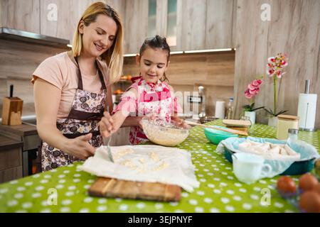 Mother-daughter joy in a bright kitchen baking together Stock Photo