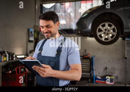 Car mechanic using a tablet in a workshop while smiling Stock Photo
