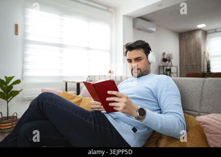 Man Reading Book on Couch Stock Photo
