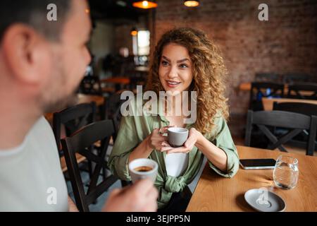 Young couple drinking coffee and talking at a cafe Stock Photo