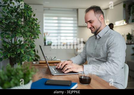 Man working from home typing on laptop Stock Photo