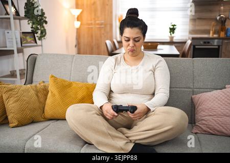 Competitive woman playing video game at home Stock Photo