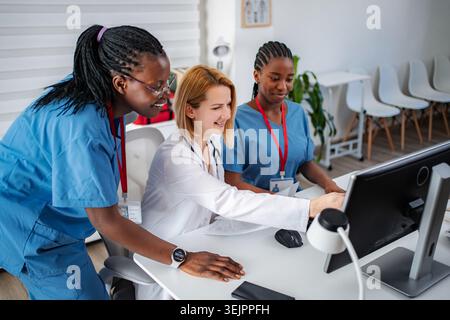 Diverse medical team collaborating on computer in healthcare setting Stock Photo