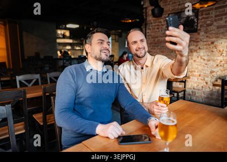 Two men taking selfie drinking beer in a bar Stock Photo