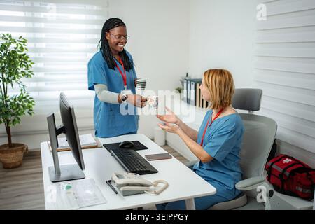 Diverse healthcare workers enjoying a coffee break in a modern hospital setting Stock Photo