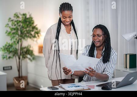 Young women collaborating on business documents in modern office Stock Photo