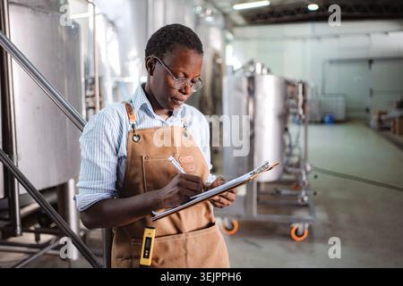 Woman working in brewery doing quality control inspection Stock Photo