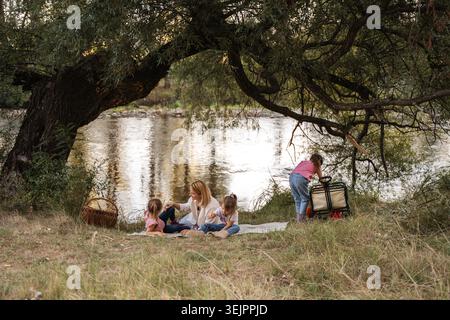 Family enjoying picnic by the river under a willow tree Stock Photo