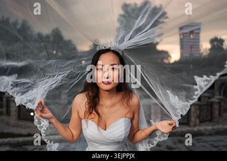 Chinese bride wearing white wedding dress and veil Stock Photo
