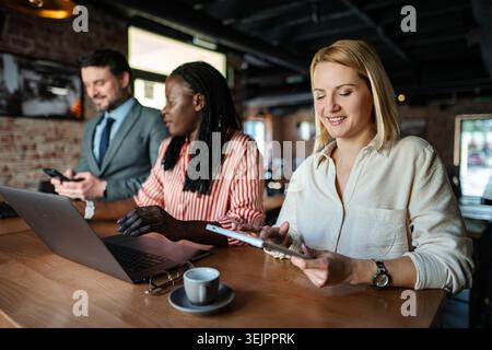Diverse business team collaborating using technology in a cafe Stock Photo